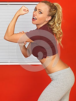 Young Attractive Woman Flexing Her Arm Muscles and Pointing photo