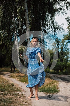 A young attractive woman with flowers in her hands walks through the forest