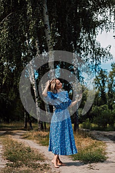 A young attractive woman with flowers in her hands walks through the forest