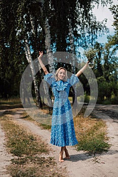 A young attractive woman with flowers in her hands walks through the forest