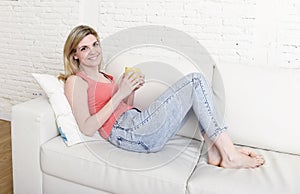 Young attractive woman holding cup of coffee sitting on sofa couch at home smiling happy