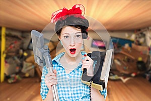 Young attractive woman holding iron and hoover