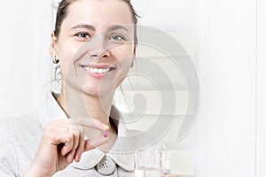 Young attractive woman holds in her hand pill and glass of clean