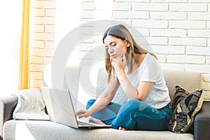 Young attractive woman at home tiredly seeking for a job or rent in internet