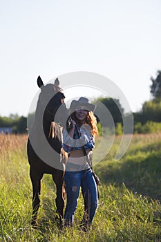 Young attractive woman and horse in the meadow at summer evening