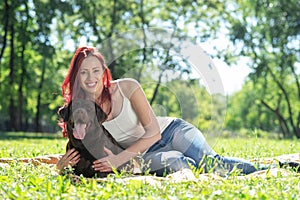 Young attractive woman hugs her dog in the park.