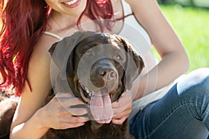 Young attractive woman hugs her dog in the park.