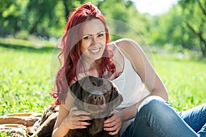 Young attractive woman hugs her dog in the park.
