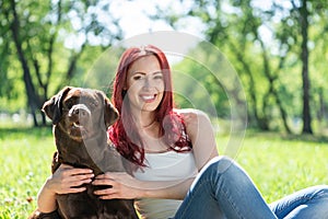 Young attractive woman hugs her dog in the park.