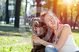 Young attractive woman hugs her dog in the park.