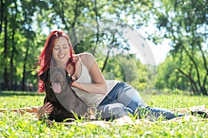 Young attractive woman hugs her dog in the park.