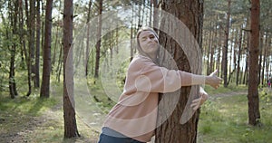 Young attractive woman hugs a tree in a summer forest park
