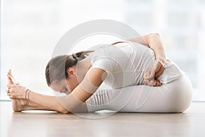 Young attractive woman in Janu Sirsasana pose against floor wind