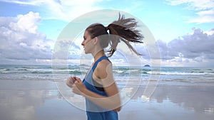 Young attractive woman jogging on the beach at sunset Beautiful clouds, sunset