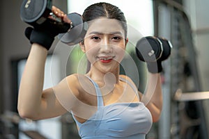 young attractive woman lifting weight in gym, indoors with equipment in the background