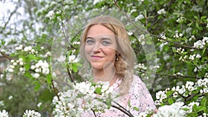 Young attractive woman with long blonde hair at the beautiful blooming sakura garden. Happy Beautiful girl in blooming trees. Beau