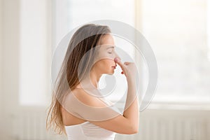Young attractive woman making Alternate Nostril Breathing, white photo