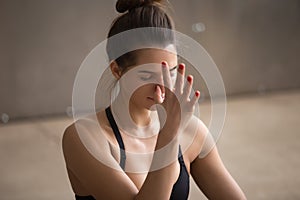 Young attractive woman making nadi shodhana pranayama, grey stud