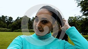 Young attractive woman making selfie on the smart phone during the running in the green park.