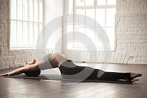 Young attractive woman in Matsyasana pose, white loft studio bac