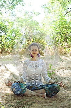 Young attractive woman meditate sitting in forest
