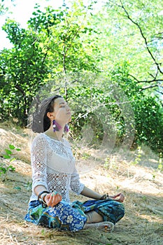 Young attractive woman meditate sitting in forest