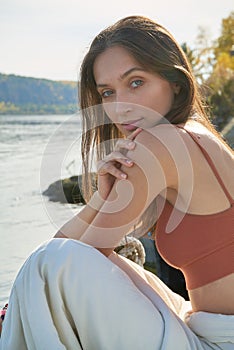 A young attractive woman of model appearance rests under a blanket on a pier. long hair