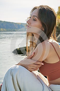 A young attractive woman of model appearance rests under a blanket on a pier. long hair