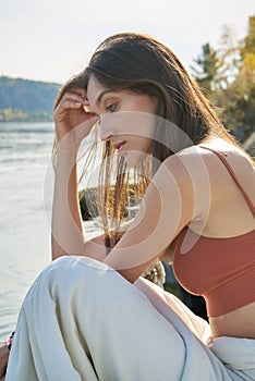 A young attractive woman of model appearance rests under a blanket on a pier. long hair