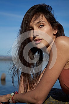 A young attractive woman of model appearance rests under a blanket on a pier. long hair