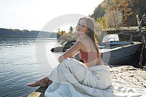 A young attractive woman of model appearance rests under a blanket on a pier. long hair