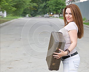 A young attractive woman with an old suitcase on the street