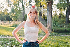 Young attractive woman outdoor holding red apple on her head and thinking about something on the blur nature background