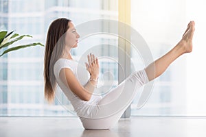 Young attractive woman in Paripurna Navasana pose against floor