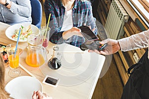 Young attractive woman paying in cafe with contactless smartphone payment