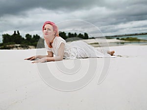Joven atractivo una mujer rosa cabello en blanco ropa en estilo sobre el de arenoso Playa 