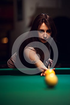 Young attractive woman playing billiard in club.