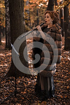 Young attractive woman playing oboe against musical stand