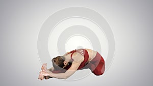 Young attractive woman practicing yoga, sitting in Head to Knee Forward Bend exercise, Janu Sirsasana pose on gradient