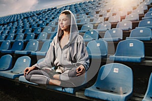 Young attractive woman practicing yoga, sitting in Padmasana exercise, Lotus pose on meditation session, working out wearing sport