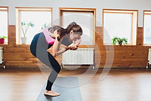 Young attractive woman practicing yoga, standing in Eagle exercise, Garudasana pose, working out, wearing sportswear