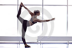 Young attractive woman practicing yoga, standing in Natarajasana exercise, Lord of the Dance pose.