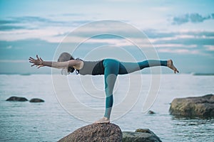 Young attractive woman practicing yoga, standing in Warrior three exercise, Virabhadrasana III pose