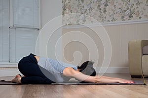 Young attractive woman practicing yoga, wearing sportswear, meditation session, home interior