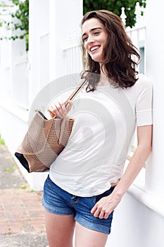 Young attractive woman with purse and leaning against fence