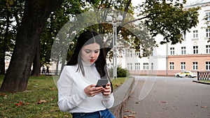 Young attractive woman reads a text message on a mobile phone