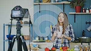 Young attractive woman recording video food blog about cooking on dslr camera in kitchen