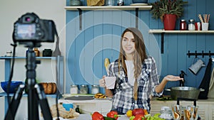 Young attractive woman recording video food blog about cooking on dslr camera in kitchen