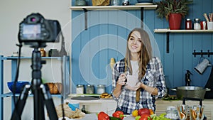 Young attractive woman recording video food blog about cooking on dslr camera in kitchen