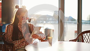 Young attractive woman in red sunglasses with tablet computer sitting in cafe. Beautiful girl in airport or shoppping